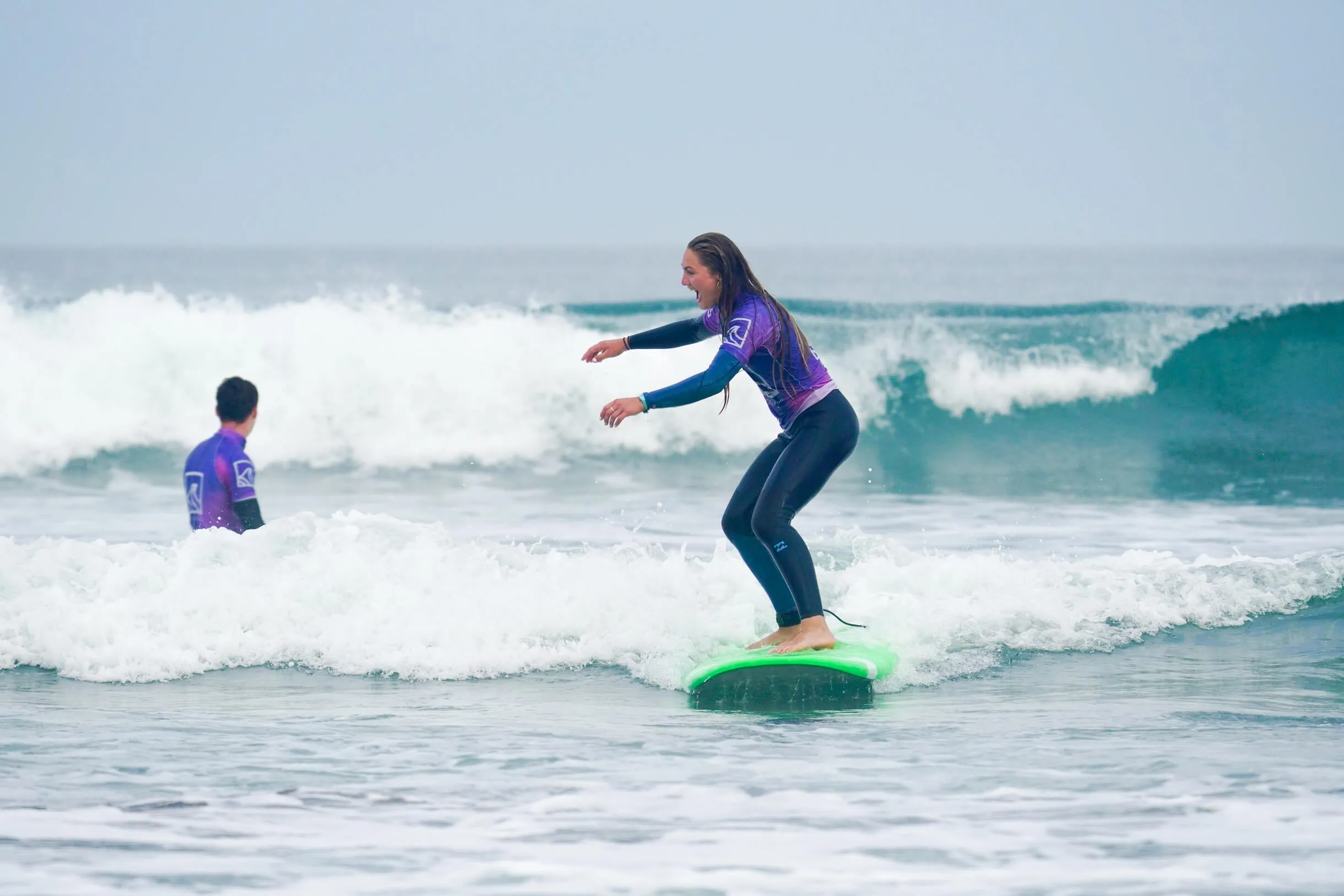 beginner surfer on a surf lesson standing on a white water wave in Widemouth Bay, Bude, Cornwall