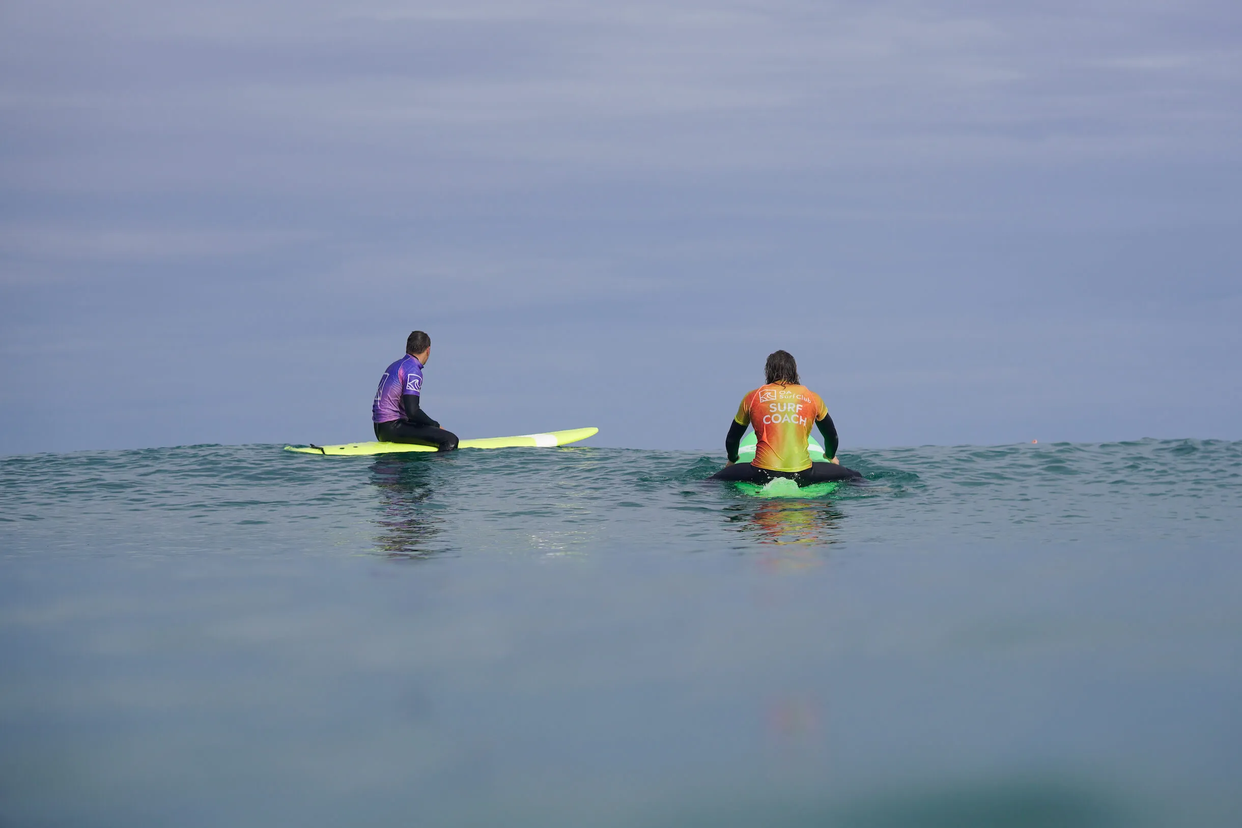private surf lesson in Bude with 2 people sitting on surfboards